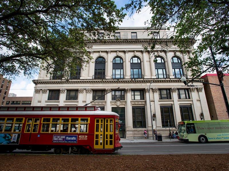 A red streetcar passes in front of the Tulane School of Social Work building
