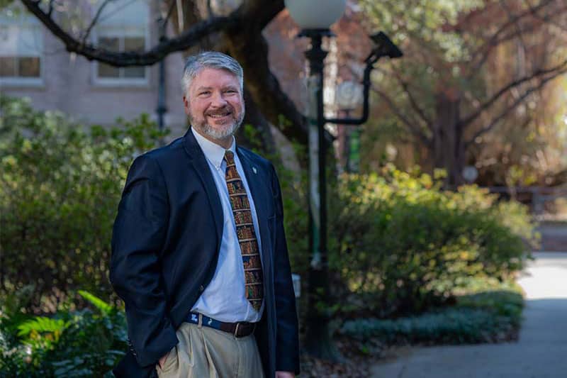 Portrait of Michael Wallace from the waist up outdoors on campus