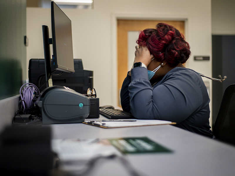 Healthcare worker rests head in hands