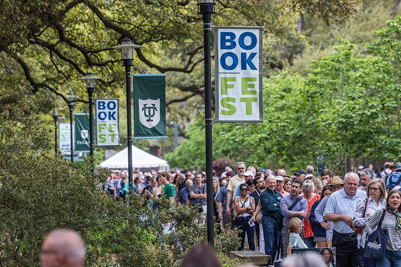Large crowd walks past "Book Fest" banners on Tulane's campus