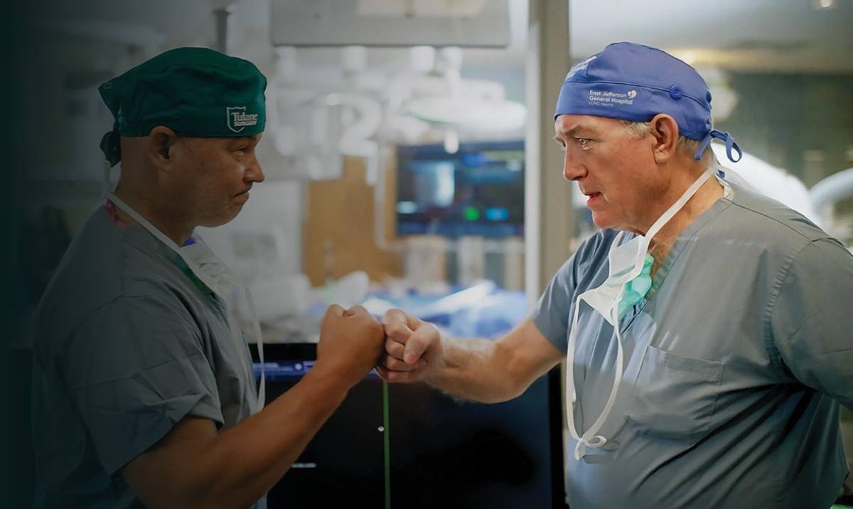 Photograph of two surgeons fist bumping in an operating room.