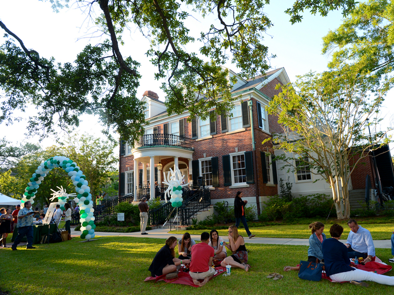 Picnickers gather on the lawn in front the Bea Field Alumni House