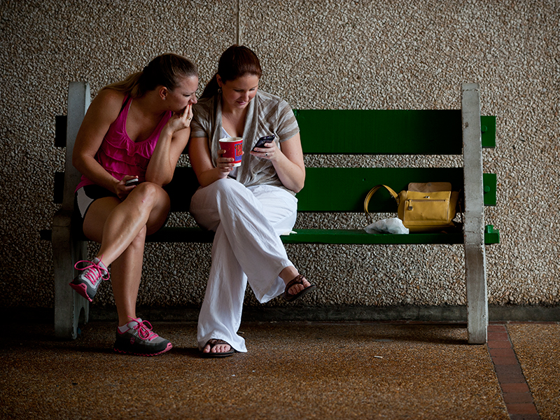 Two people on a bench looking at a smart phone