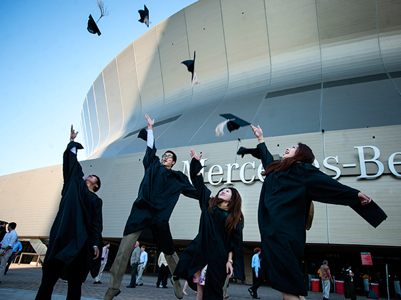 Graduates throw their caps in the air outside the Mercedes-Benz Superdome