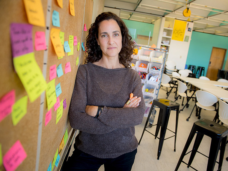 Allison Schiller,design thinking project manager for the Phyllis M. Taylor Center for Social Innovation and Design Thinking, stands in front of a board marked with post its in a classroom.  