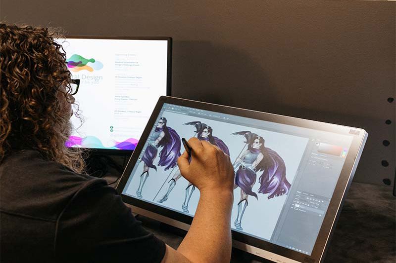 A digital design student draws on a tablet