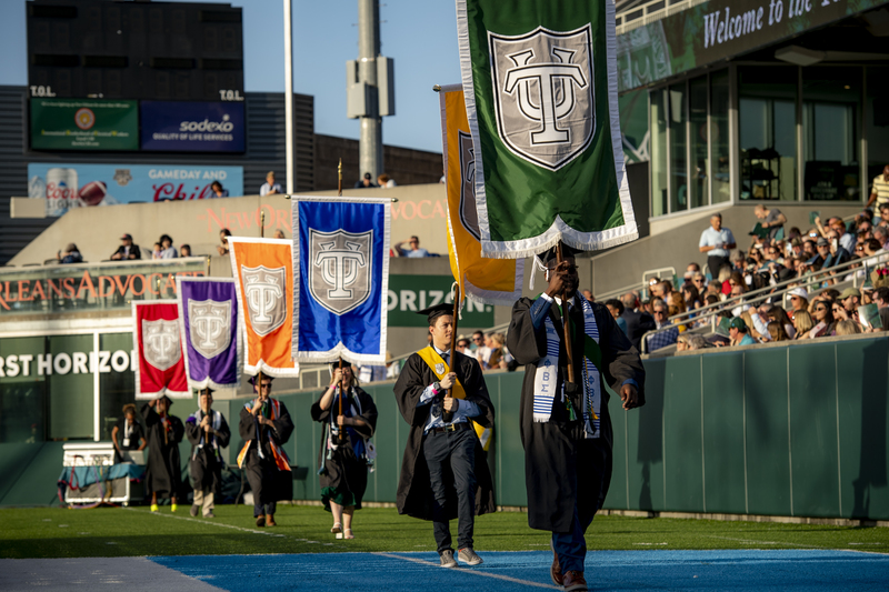 Graduates process into Yulman carrying gonfalons