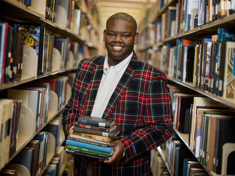 Jalon Young holding books in library