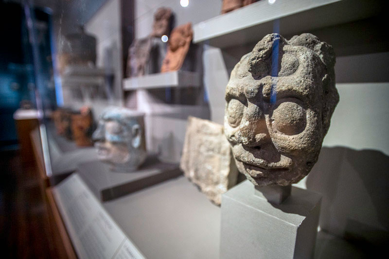 A sculptural head representing the Mayan sun god, K’inch Ajaw, sits in a display case in the Middle American Research Institute exhibit “Faces of the Maya: Profiles in Continuity and Resilience.”