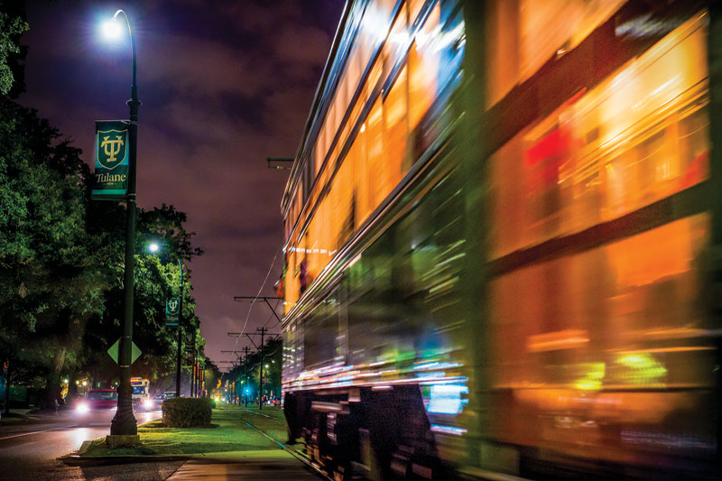 A streetcar zips down St. Charles Avenue at night