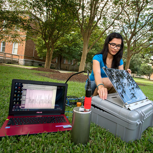 A girl sits outside with her computer studying. 