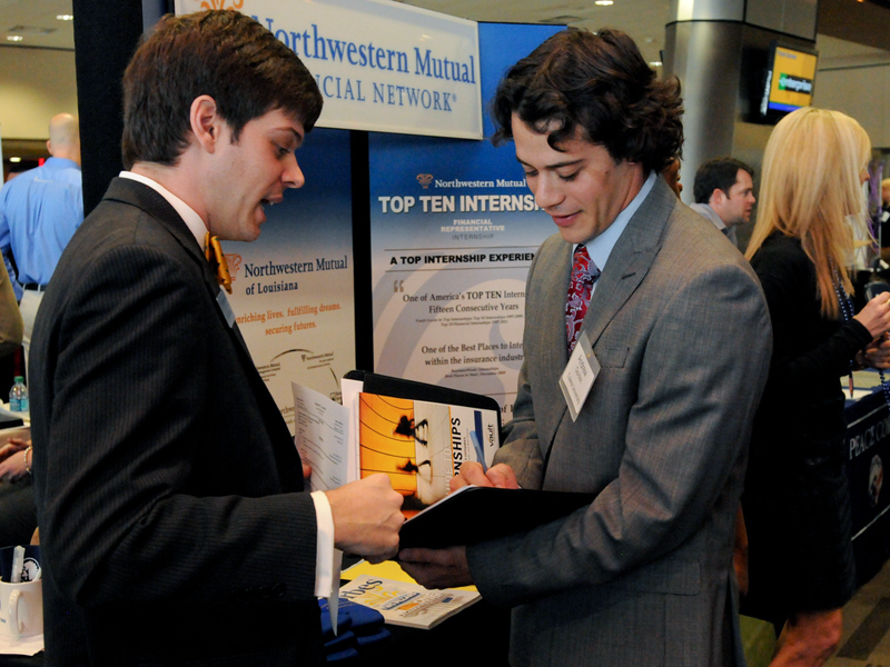 A recruiter and student look over information packet at job fair
