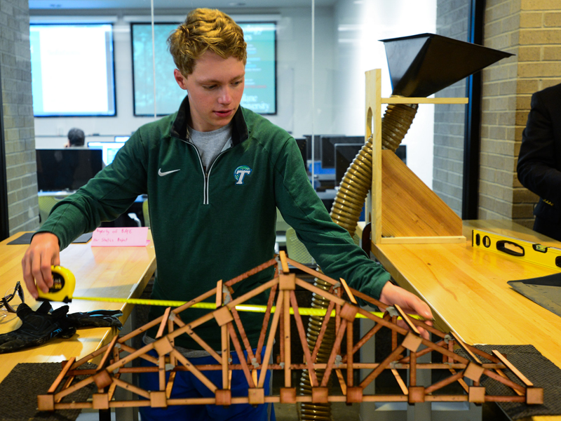 Student uses measuring tape while participating in truss building