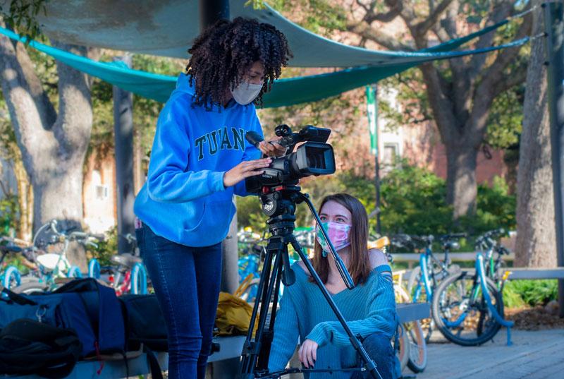 Two students set up video camera and tripod on uptown campus