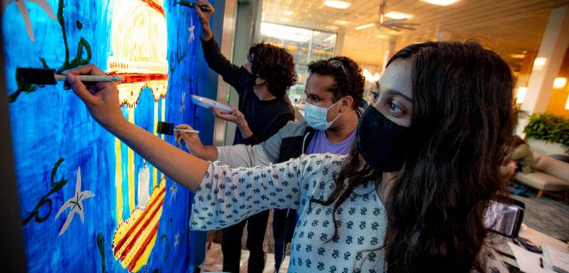 Three students paint windows in the LBC